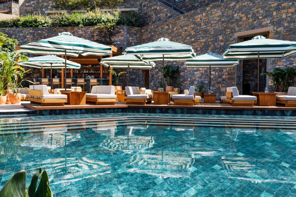 Daios Cove Luxury Resort baseins ar sauļošanās krēsliem un lietussargiem