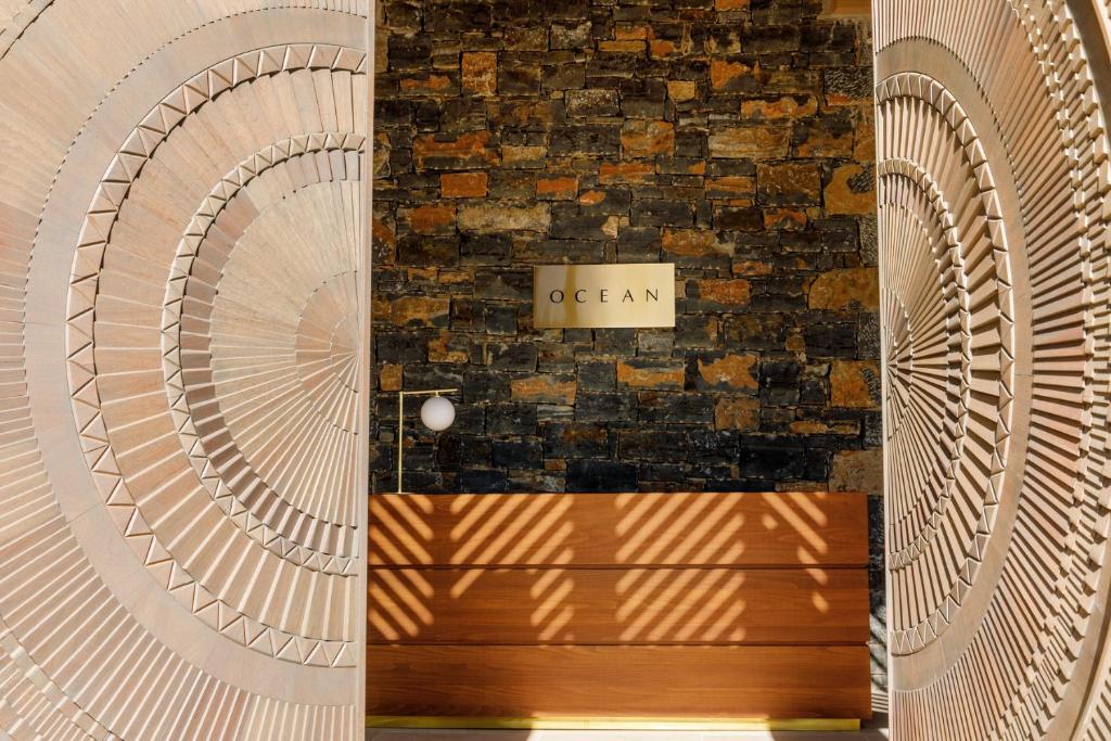 Ieeja uz OCEAN restorānu Daios Cove Luxury Resort ar akmens sienu un dekoratīvām durvīm