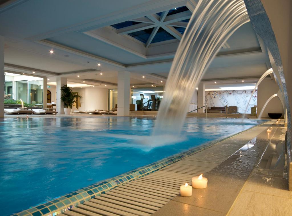 Mūsdienīgs spa ar lielu baseinu, kas piedāvā relaksējošu atmosfēru un ūdens straumi. Ap galu ir novietotas sveces, radot mierīgu noskaņu.