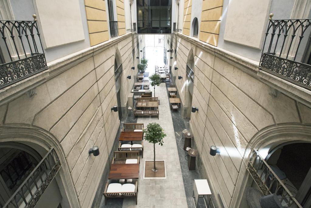 Mūsdienīgs interjers ar atvērtu telpu, kurā atrodas koka galdi un krēsli, kā arī augi, kas piešķir dzīvesprieku. Šī arhitektūra apvieno eleganci un komfortu.