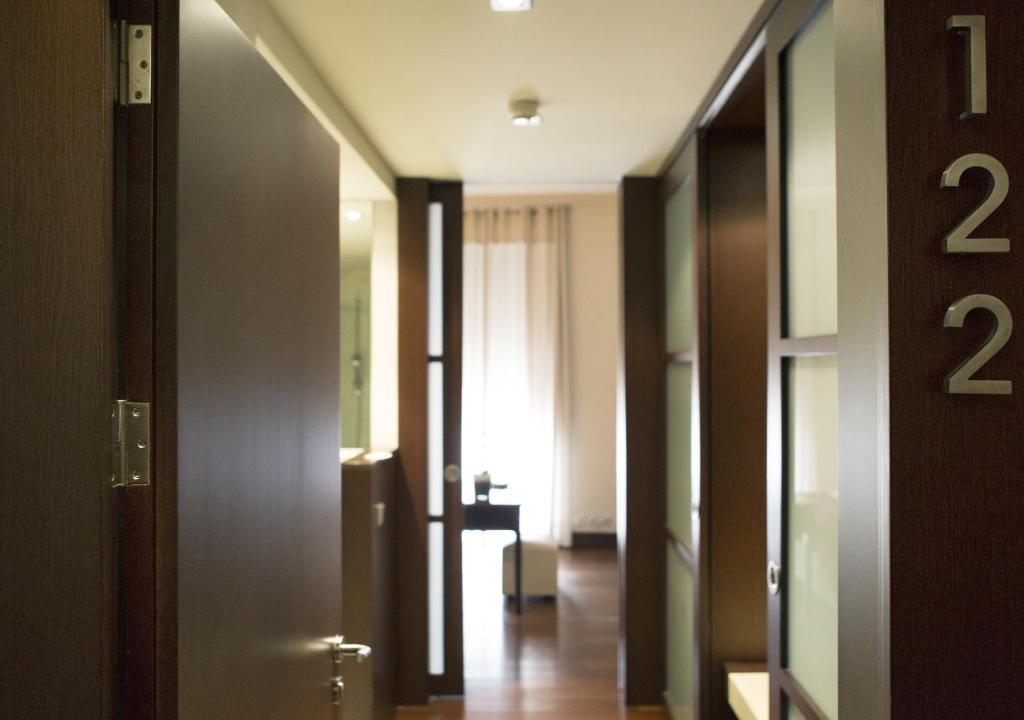 Kāzu numura durvis un gaiss, kas ved uz mūsdienīgu interjeru, kurā redzama gaisma un mēbeles. Numura numurs "122" ir redzams uz durvīm.