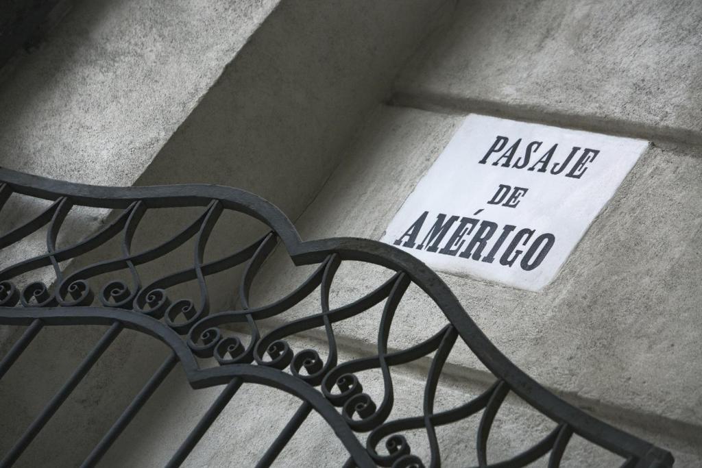 Pasāža ar nosaukumu "Pasaje de Amérigo", kas redzama uz sienas, ar dekoratīvu dzelzs žogu priekšā.