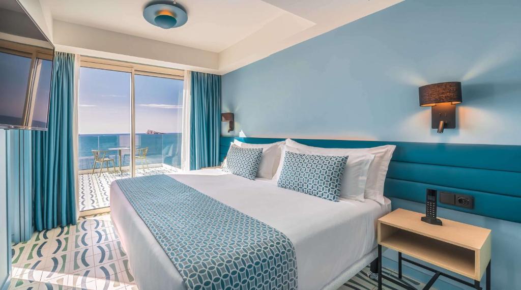 Mūsdienīgs viesnīcas numurs ar skatu uz jūru, kurā ir divguļamā gulta un balkons. Interjers ir veidots gaišos zilajos toņos, radot relaksējošu atmosfēru.
