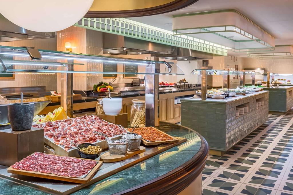 Mūsdienīgs bufetes stils ar dažādiem gaļas izstrādājumiem un uzkodām, kas izkārtoti eleganti ar zaļiem akcentiem un modernu apgaismojumu. Ideāli piemērots gardēžiem un svinībām.