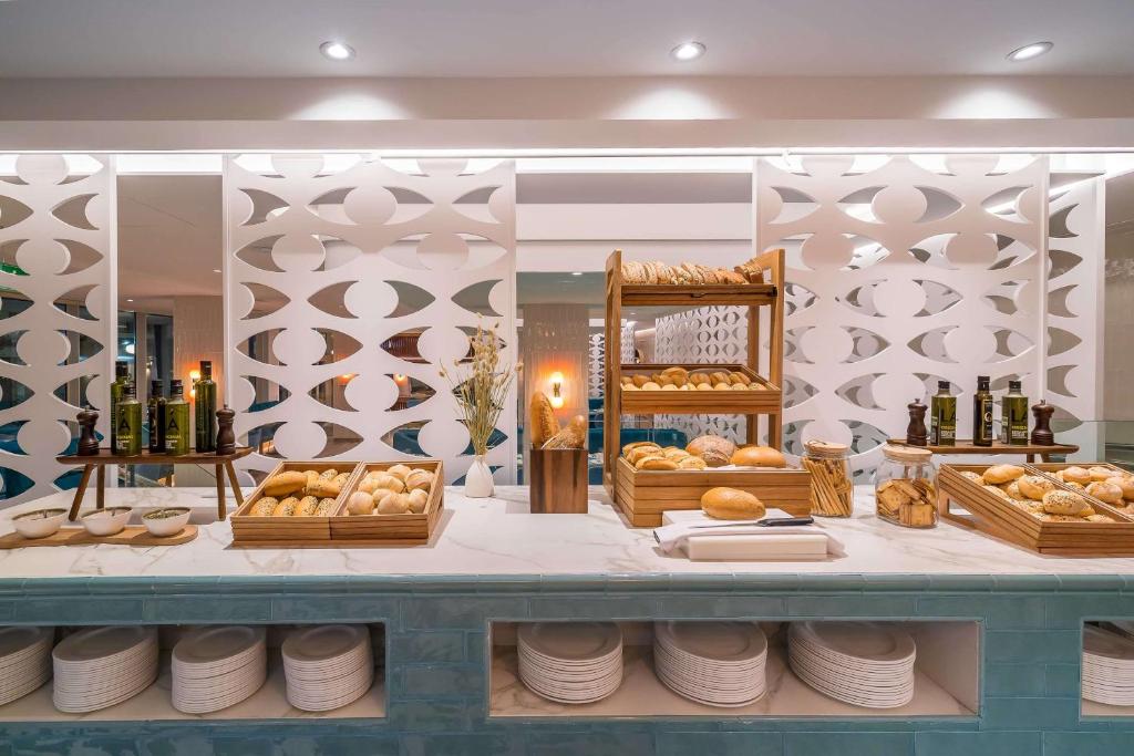 Pusdienu bufete ar dažādiem maizes veidiem un olīveļļas pudelēm, elegantā un modernā vidē. Galda dekors ietver koka traukus un stilīgas apkalpošanas iespējas.