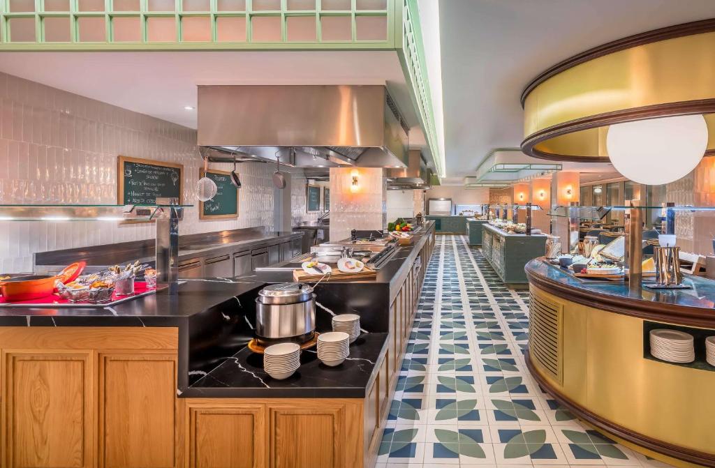 Mūsdienīgs restorāna interjers ar elegantām mēbelēm un plašu bufetes galdu, piedāvājot dažādus ēdienus un dzērienus. Labi apgaismots ar modernām lampām un stilīgu flīžu grīdu.