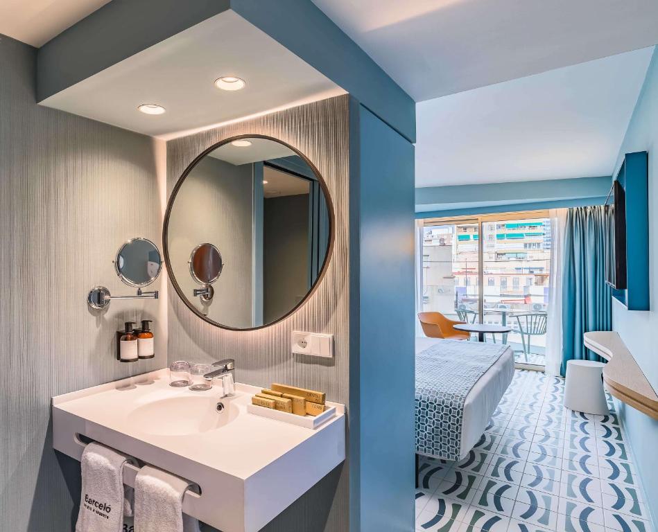 Mūsdienīgs viesnīcas numurs ar elegantu vannas istabu, apaļu spoguli un skatu uz pilsētu. Iekārtojums apvieno komfortu un stilīgu dizainu.