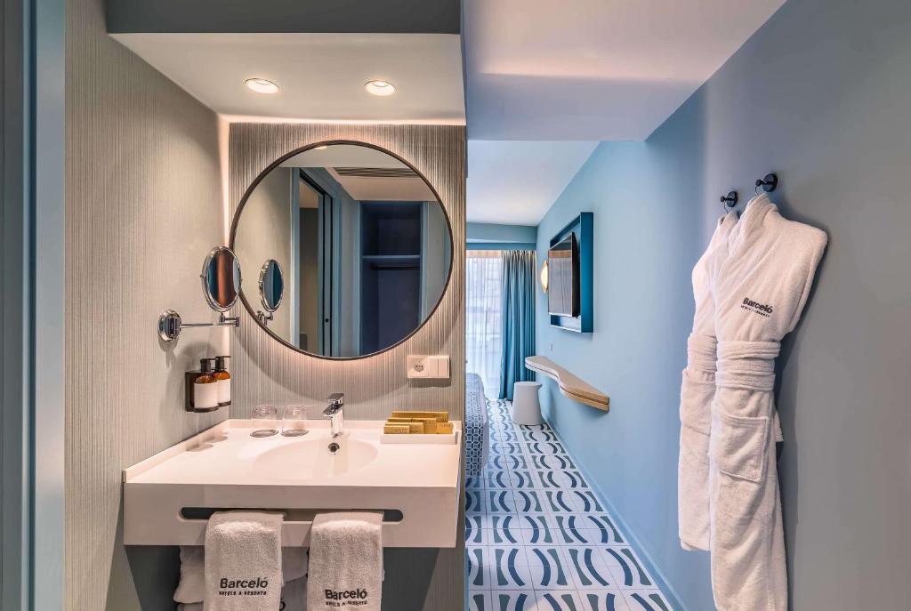 Moderns viesnīcas numura interjers ar elegantu vannas istabu, aploksni un mūsdienīgu dizainu. Balts dvielis un vannas piederumi piekārti pie sienas, veidojot greznu atmosfēru.