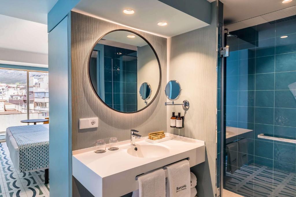 Mūsdienīgs vannas istabas interjers ar apaļu spoguli un gaišām flīzēm. Svaigs un stilīgs dizains ar skatu uz pilsētu.