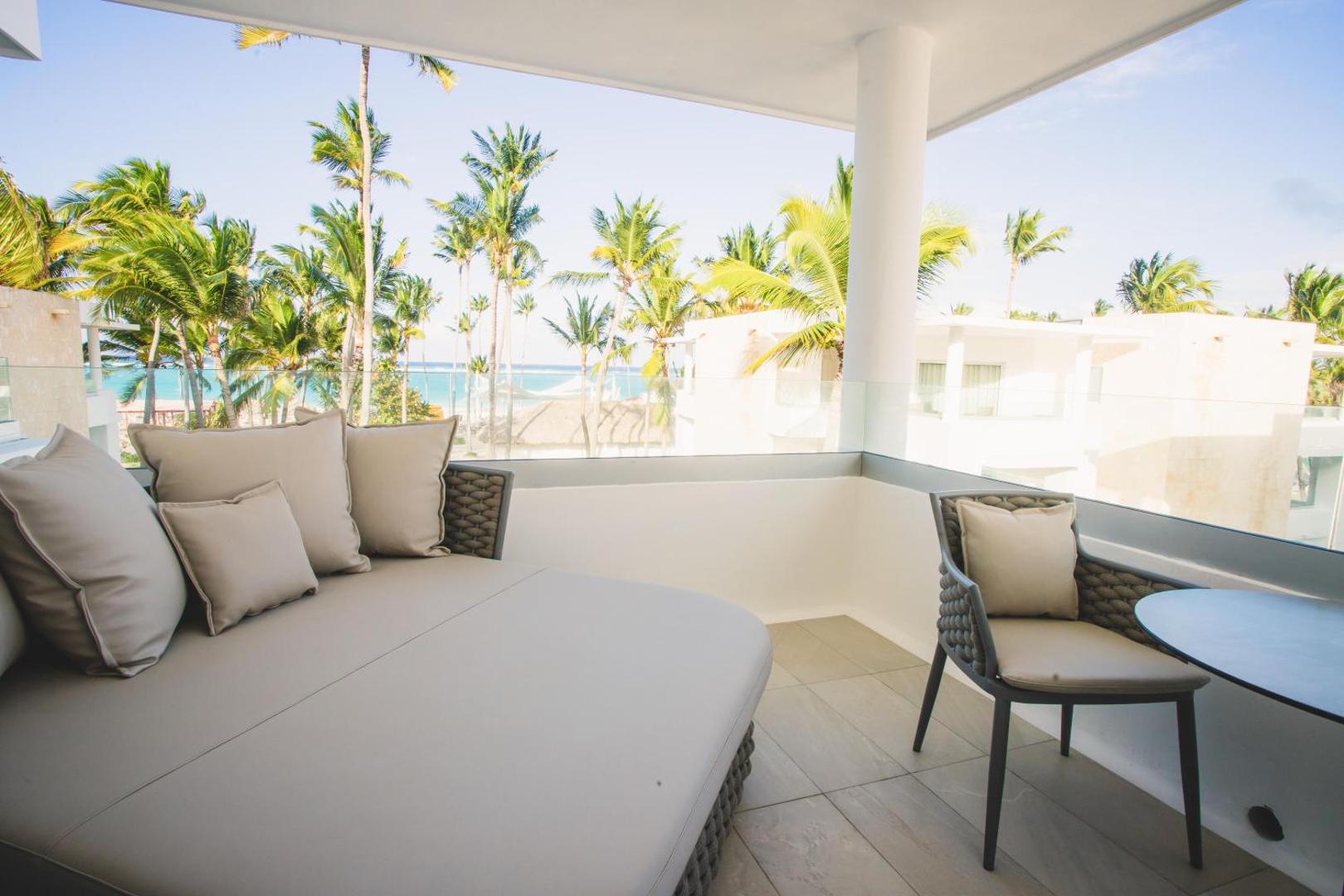 Grand Bavaro Princess plaša terase ar ērtu atpūtas gultu un skatu uz palmām un okeāna piekrasti