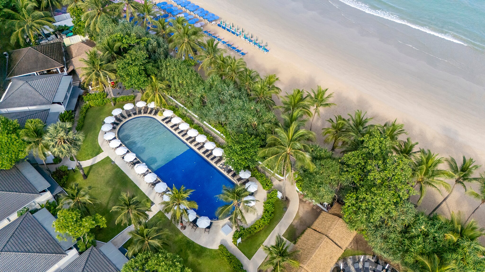 Sunwing Resort Kamala Beach skats no putna lidojuma uz āra baseinu, palmu dārzu un smilšu pludmali Kamala Beach.