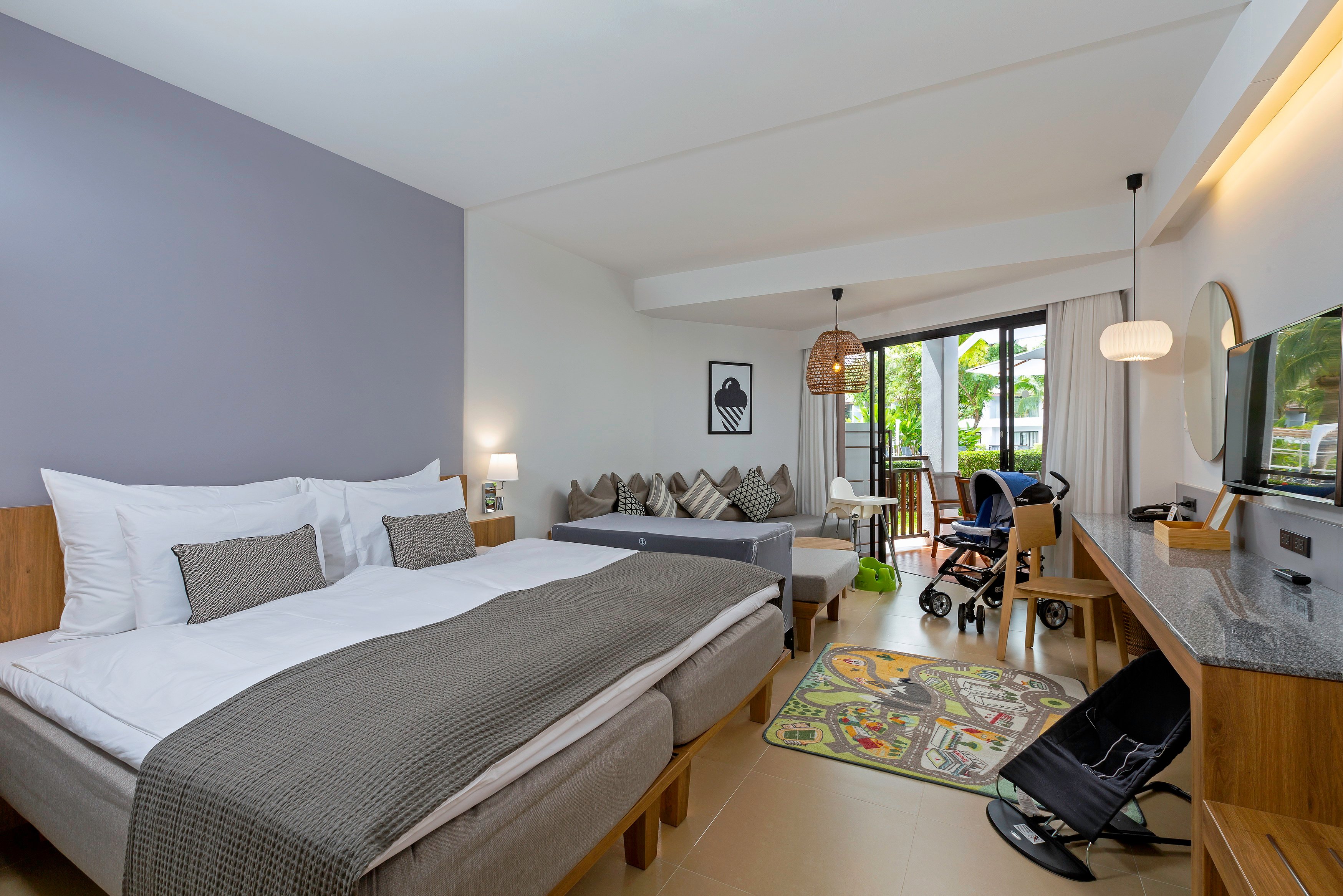 Sunwing Resort Kamala Beach plašs ģimenes numurs ar divguļamo gultu, bērnu gultiņu, rotaļu paklāju un piekļuvi balkonam.