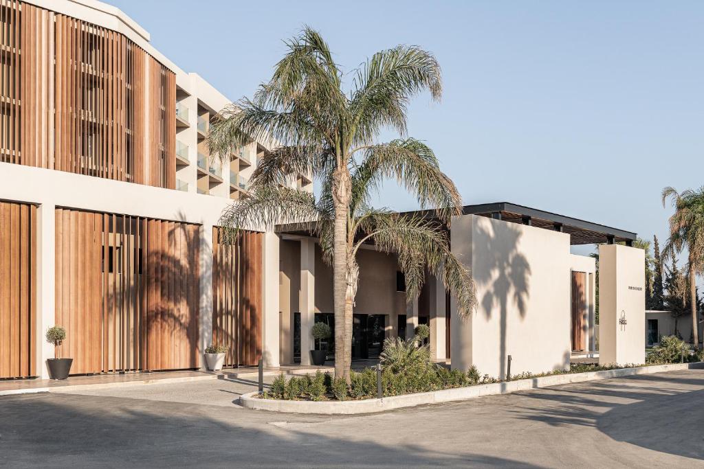 Helea Lifestyle Beach Resort modernas ēkas ieeja ar palmām