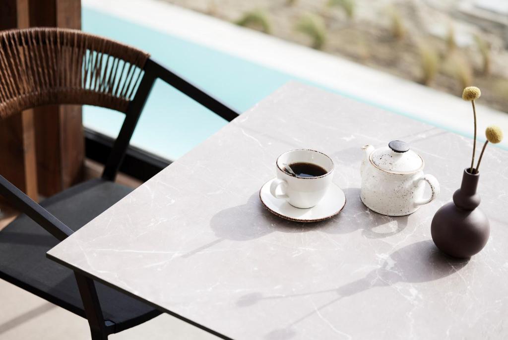 Kafijas tasi un tējas kanna uz galda Helea Lifestyle Beach Resort.