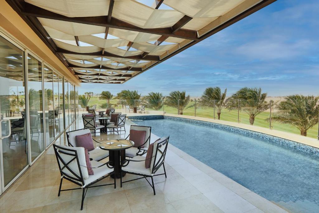 Relaksējoša terase pie Steigenberger Makadi ar baseinu un skatu uz ainavu.