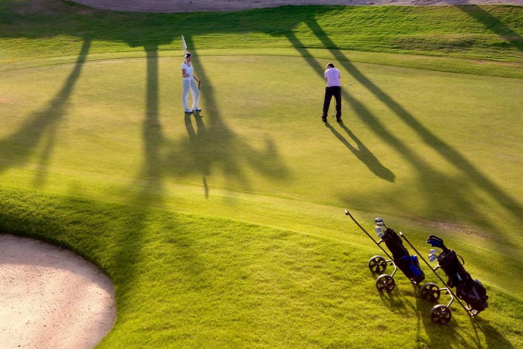 Golfa spēlētāji pie Steigenberger Makadi golfa laukuma, zaļš fons.