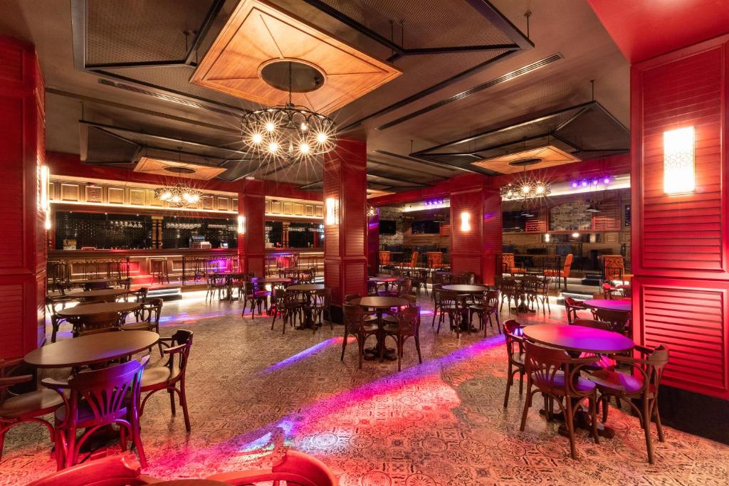 Mūsdienīgs bārs viesnīcā Swandor Hotels & Resorts Topkapi Palace ar sarkanām sienām un stilīgu apgaismojumu.