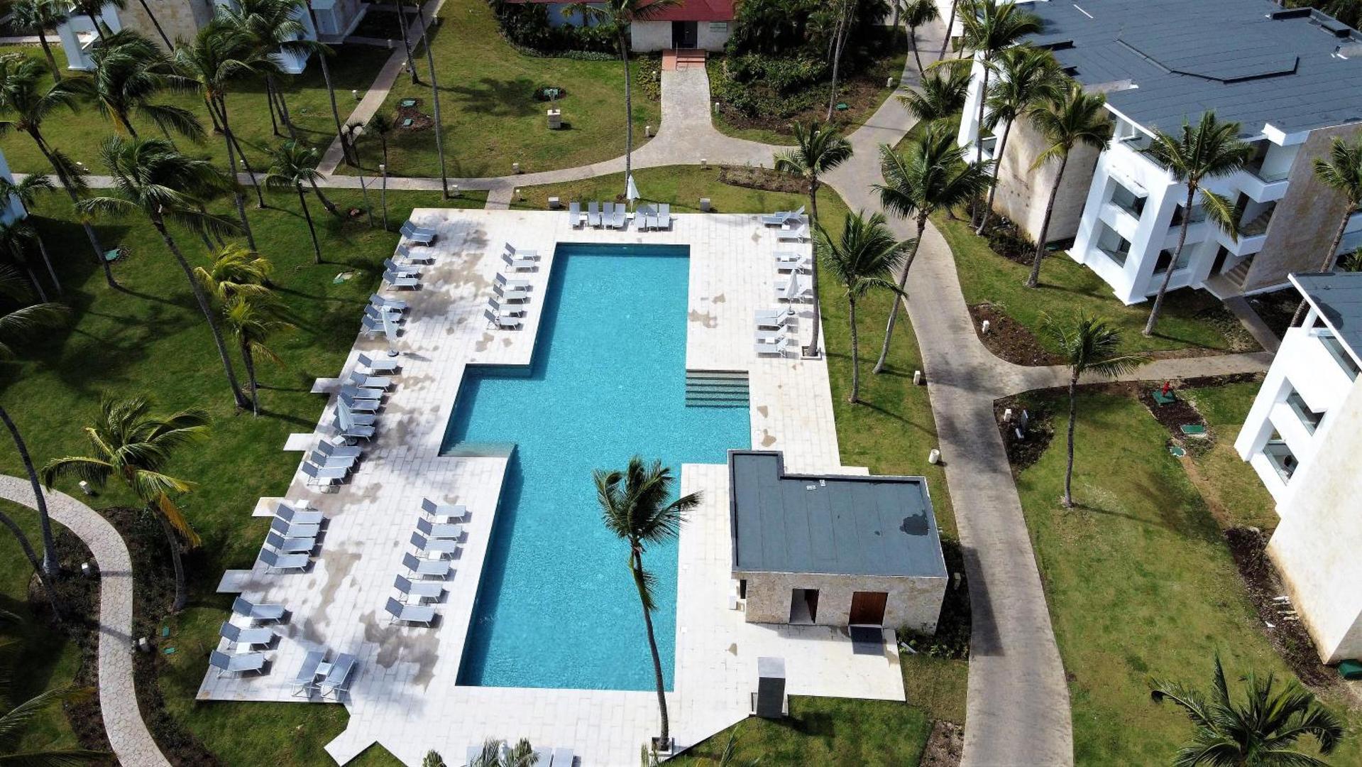 Grand Bavaro Princess viesnīcas teritorijas skats no augšas uz baseinu, dārzu un modernajiem numuru korpusiem
