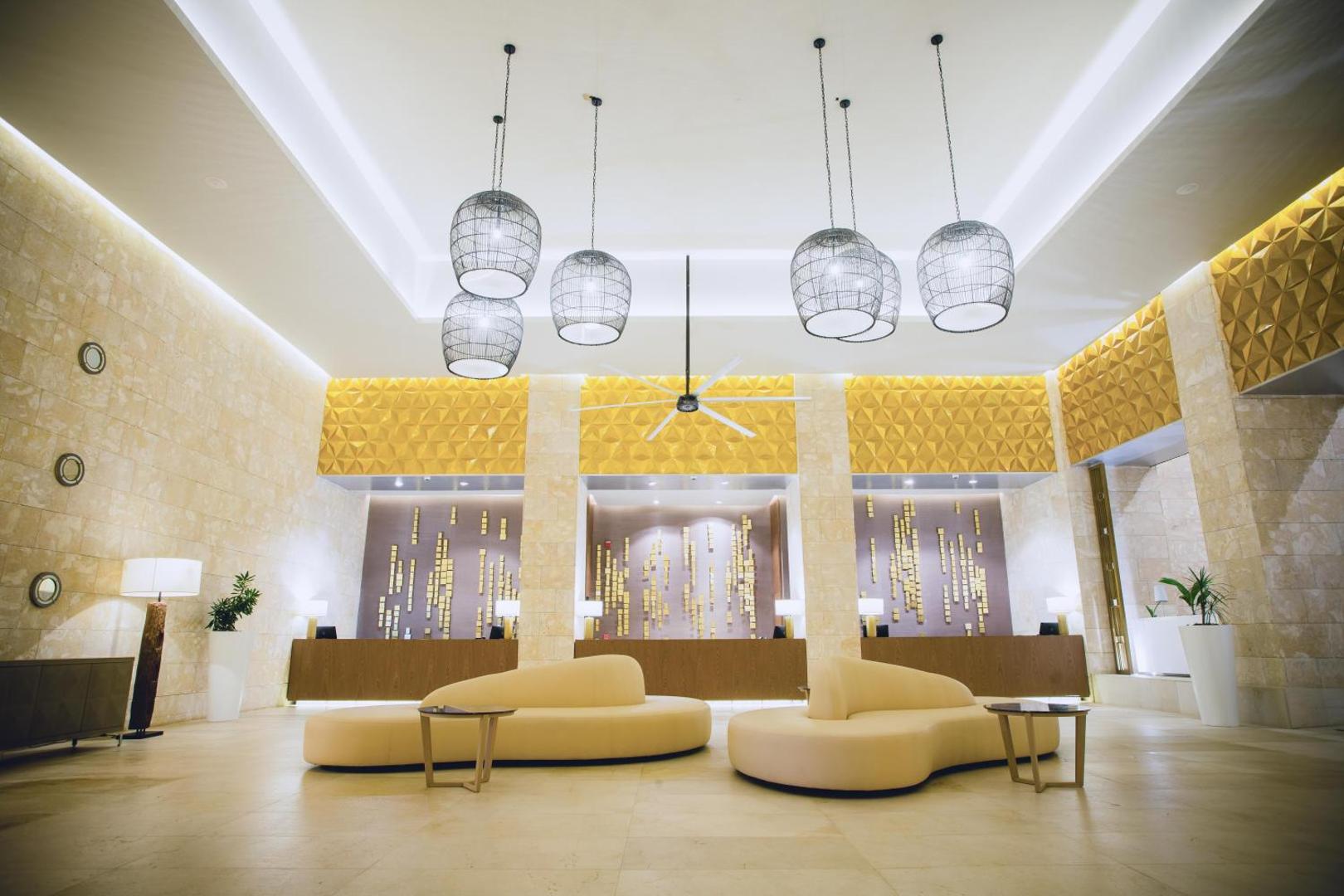 Grand Bavaro Princess viesnīcas plašais un modernais vestibils ar dizaina dīvāniem, augstiem griestiem un dekoratīviem gaismekļiem Punta Kanā, Dominikānā