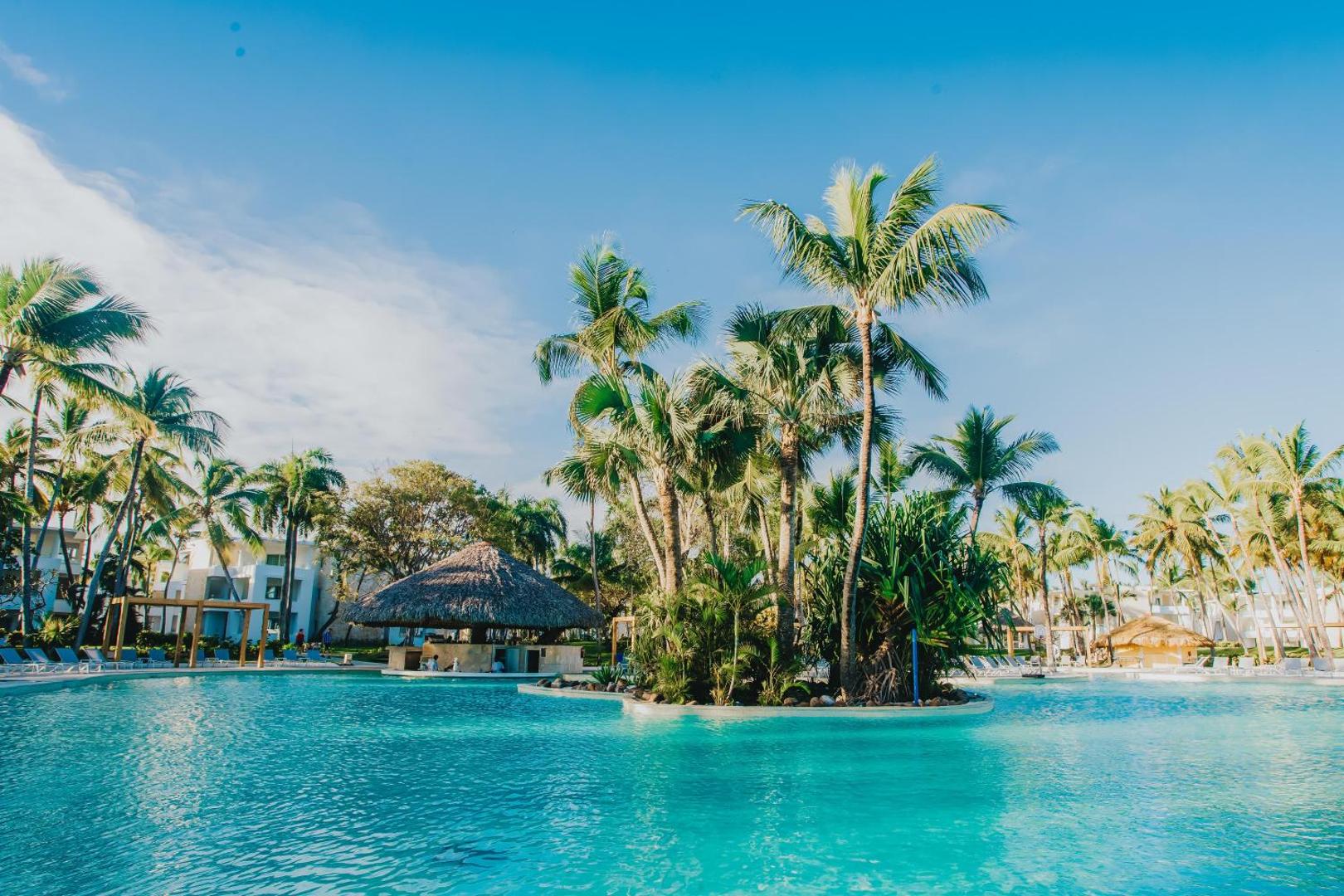 Grand Bavaro Princess plašais lagūnas tipa baseins ar tropu salu un tradicionālu niedru jumta bāru