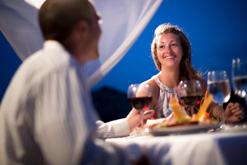 Romantiska vakariņas diviem ar vīnu un gardu ēdienu, fonā zili debesu toņi.