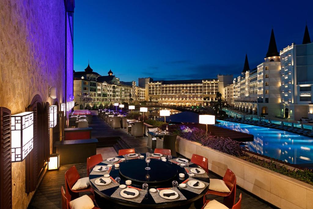 Skaista nakts skats uz Titanic Mardan Palace ar ēdamgaldu un baseinu.