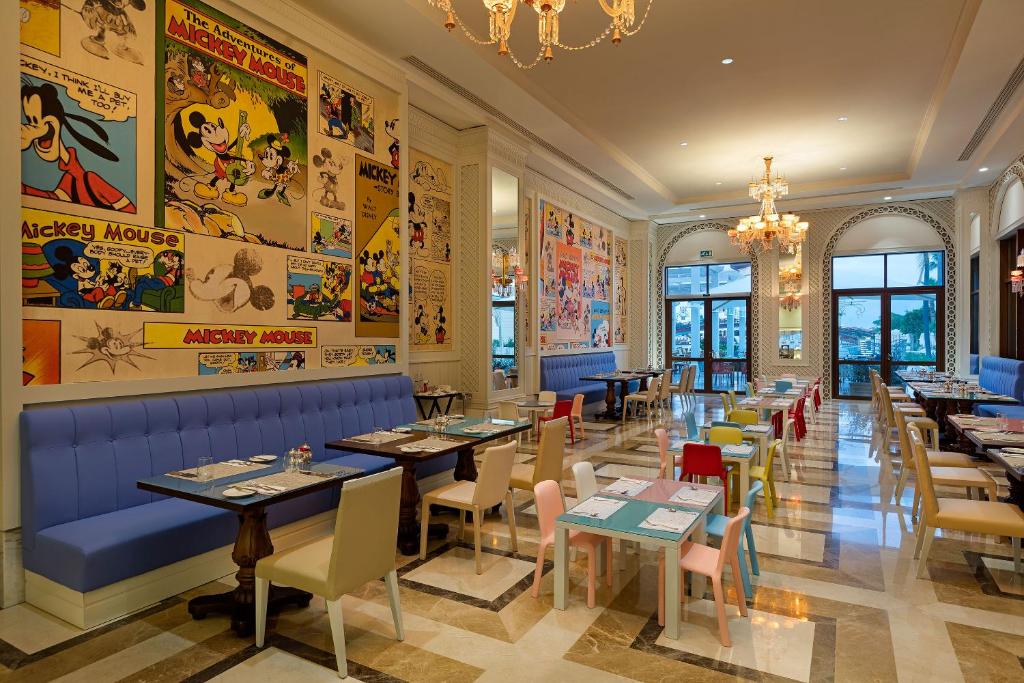 Mickey Mouse tematizēts restorāns Titanic Mardan Palace ar krāsainiem galdiem.