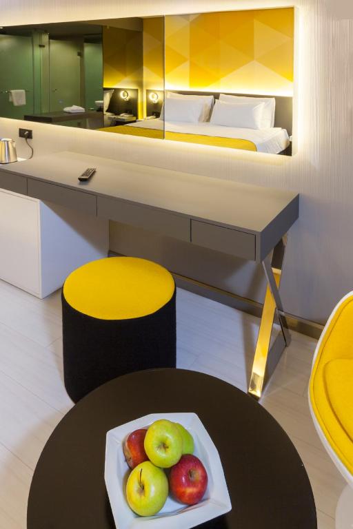 Mūsdienīgs numurs Bosphorus Sorgun Hotel ar dzeltenām akcentiem un augļiem.