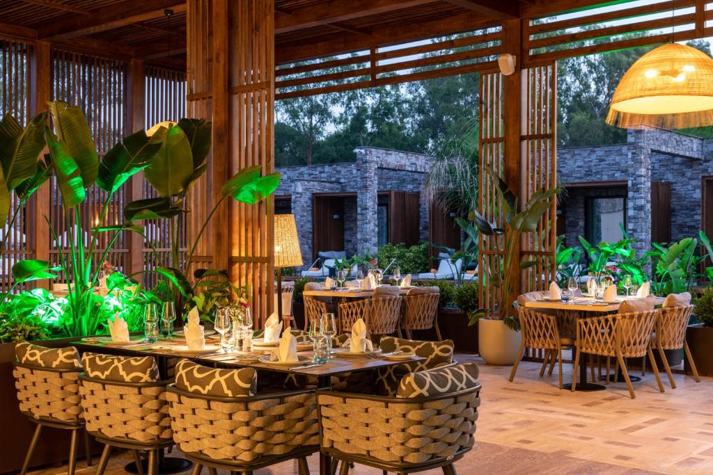 Kaya Palazzo Golf Resort eleganta restorāna iekšskats ar tropiskām augiem.