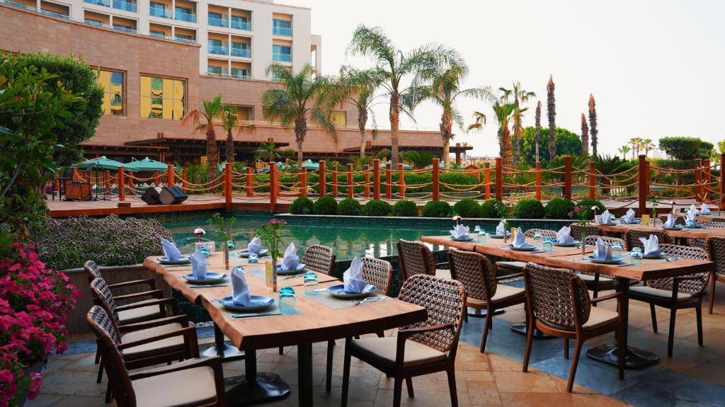 Kaya Palazzo Golf Resort restorāns pie baseina ar galdiem un palmām