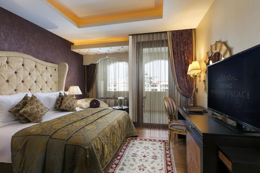 Elegants numurs Titanic Mardan Palace ar greznu gultu un skatu uz dārzu.