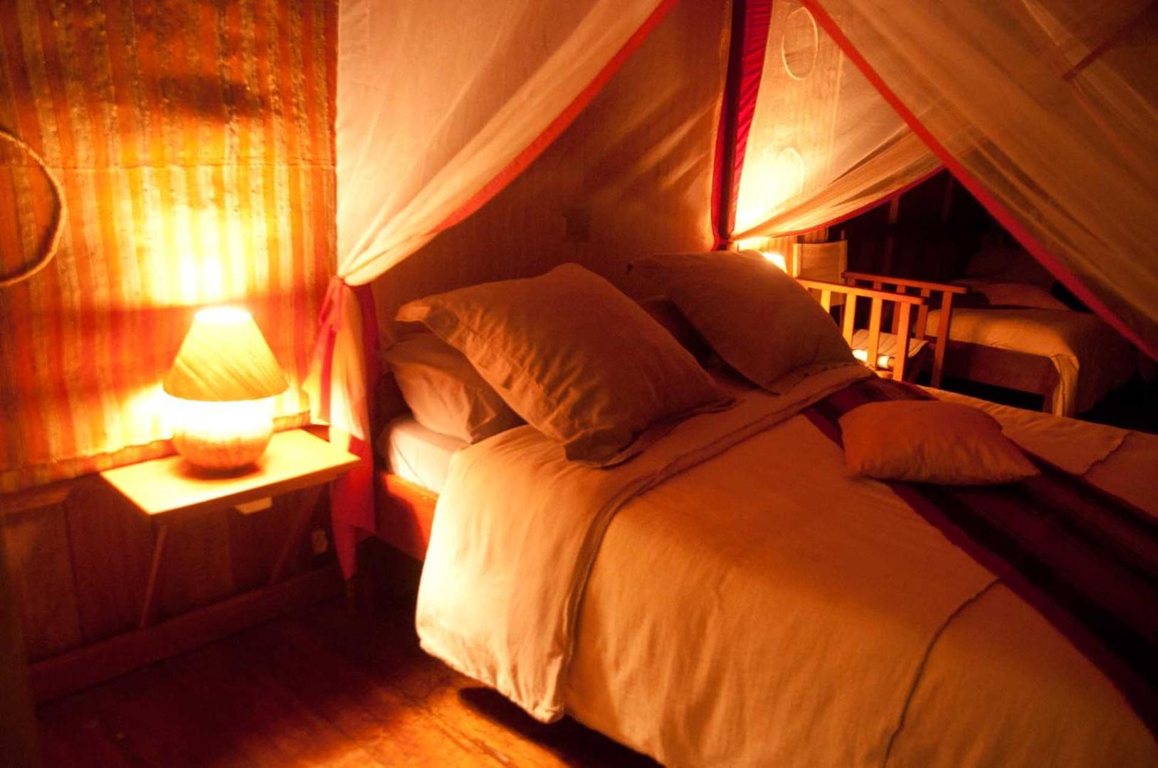 Gulta ar moskītu tīklu un siltu apgaismojumu vakara noskaņās.