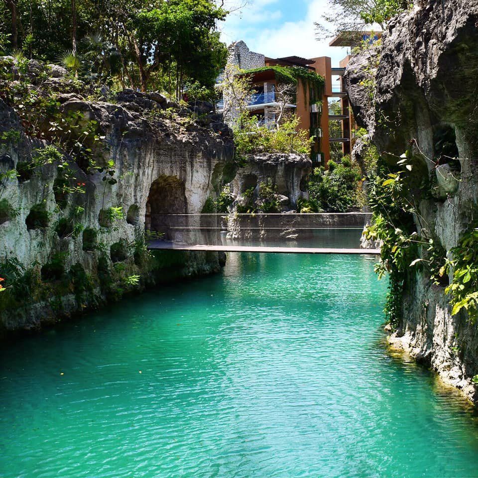 Xcaret Mexico viesnīca pie tropiskās upes ar akmeņainiem krastiem.
