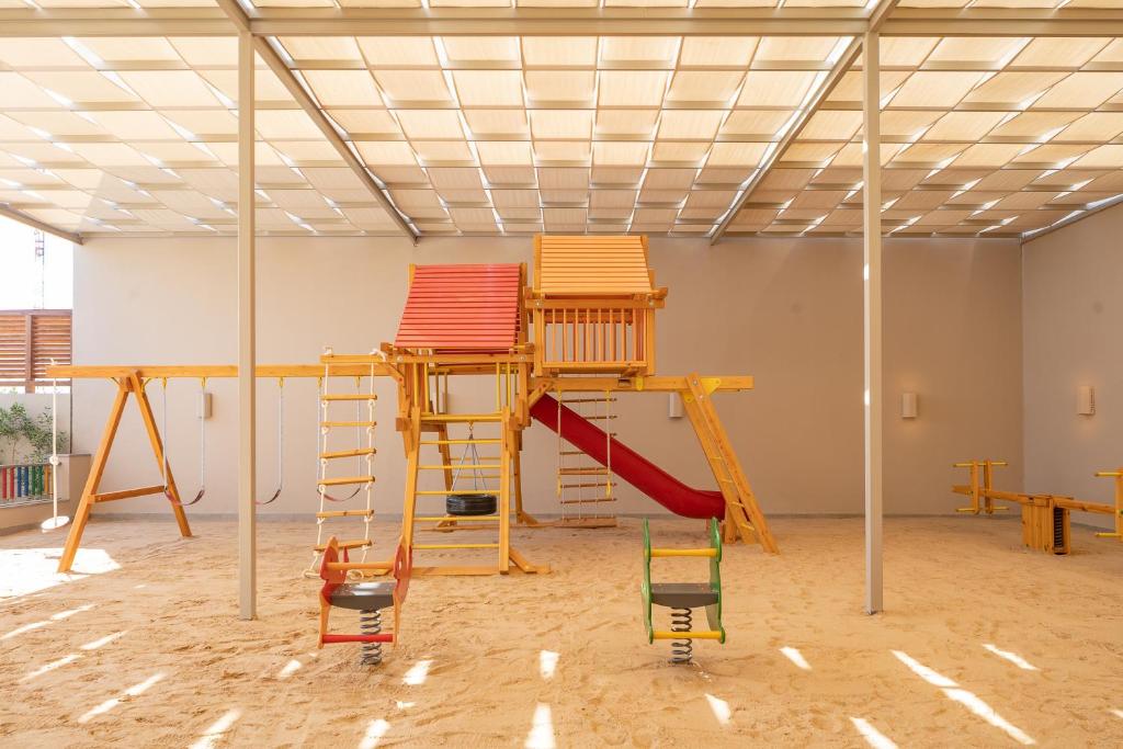 Bērnu rotaļu laukums Steigenberger Resort Ras Soma ar smilšu segumu un šūpolēm.