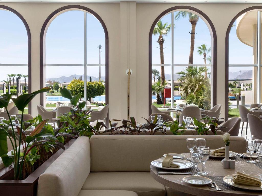 Skats uz Pickalbatros Golf Luxury Suites restorānu ar palmām un baseinu