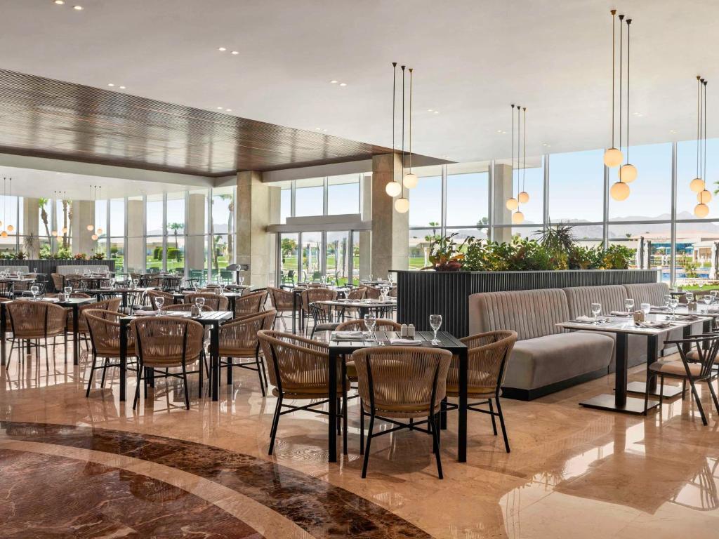 Mūsdienīgs restorāns viesnīcā Pickalbatros Golf Luxury Suites ar elegantiem galdiem