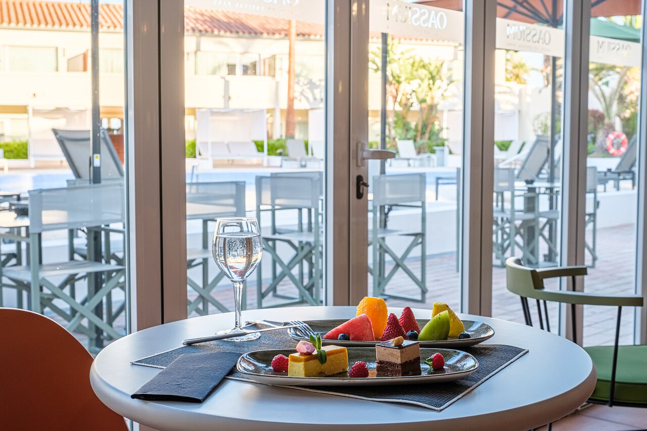 Svaigi augļi un deserti uz galda Oassium Hotel - Adults Only ar skatu uz saulaino baseina terasi.