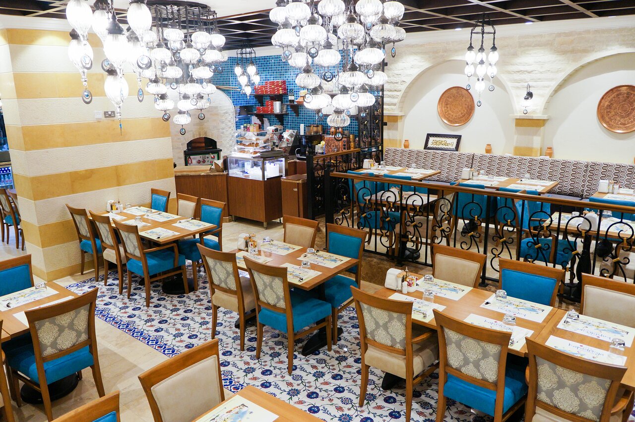 Restorāns Rose Park Hotel Al Barsha ar elegantām mēbelēm un gaismekļiem.