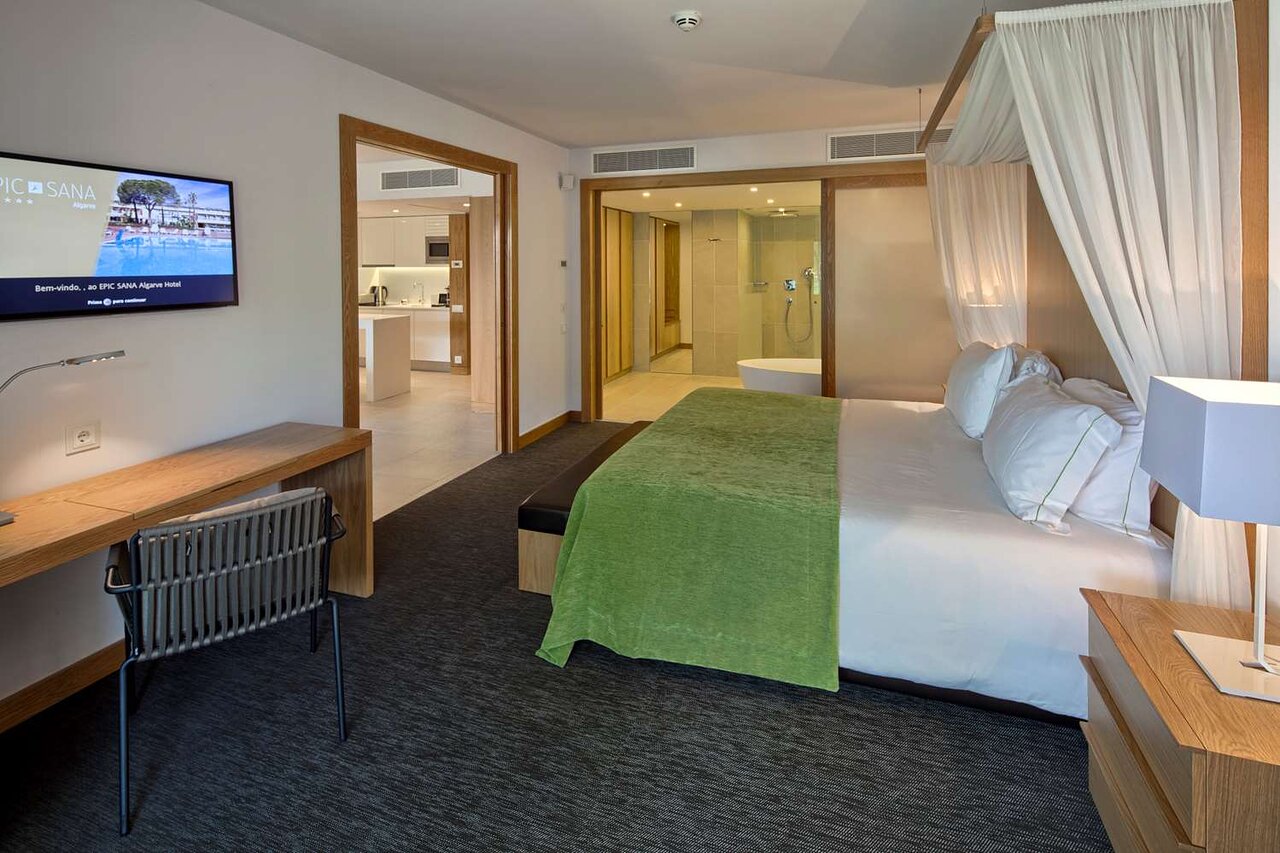 Plašs EPIC SANA Algarve Hotel numurs ar atvērtā plānojuma vannas istabu un virtuves zonu.