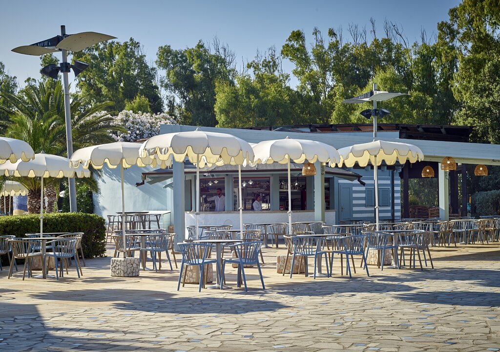 Āra kafejnīca pie Serene Resort ar saulessargiem un galdiem