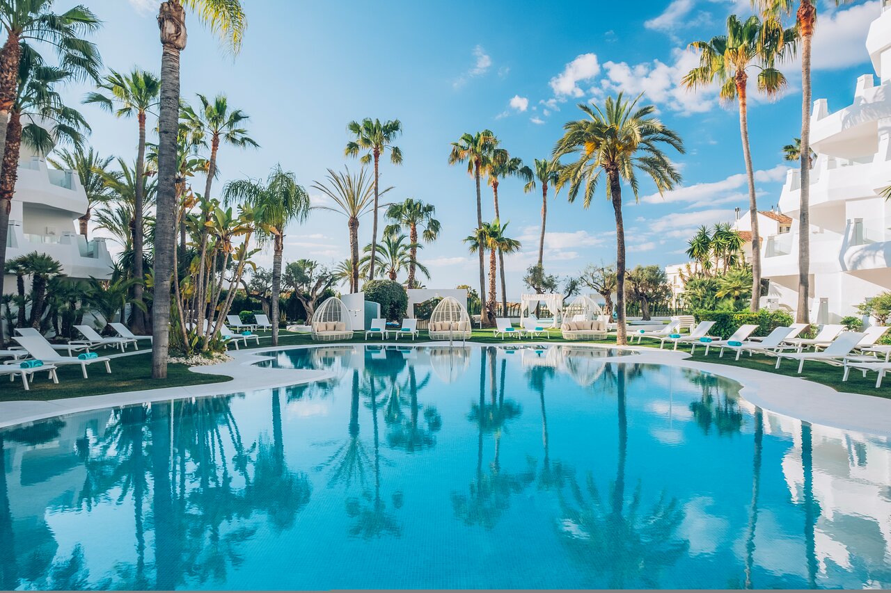 Luksusīgs baseins ar palmām un saulessargiem, apkārtne ir zaļa un labi kopta. Ideāla atpūtas vieta saulainā dienā. panoramic view with beach and pools