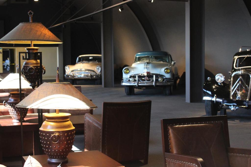 Viesnīcas Paloma Perissia interjers ar vintage automašīnām un elegantiem gaismekļiem.