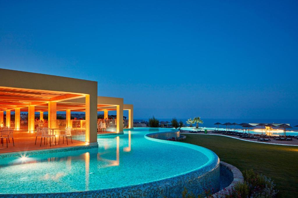 Atlantica Aegean Blue viesnīcas baseins ar apgaismojumu piekrastē vakarā