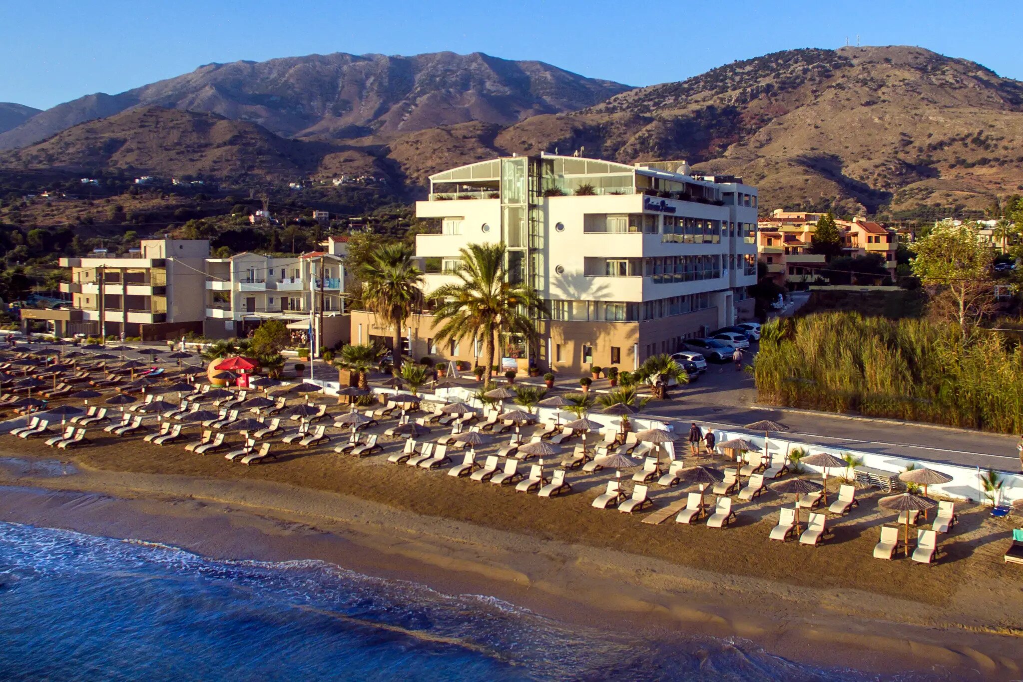 Pludmales viesnīca ar modernu arhitektūru, apkārtējās kalnu ainavas un šūpuļtīkliem pludmales zonā. Ideāla vieta relaksācijai pie jūras. panoramic view with beach and pools