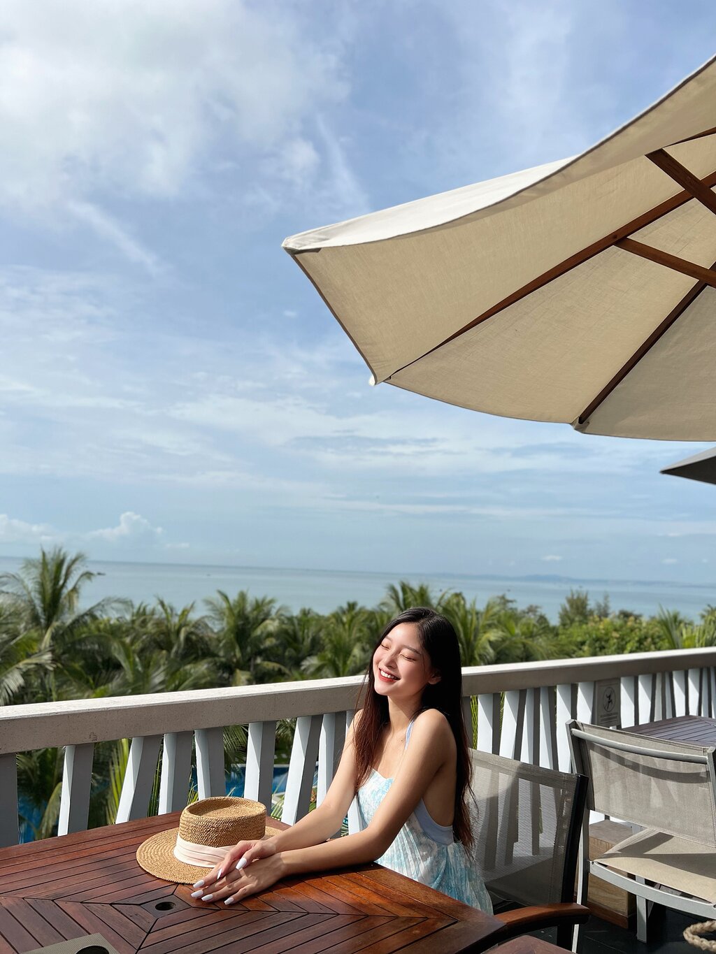Sieviete atpūšas The Cliff Resort & Residences terasē ar skatu uz jūru.