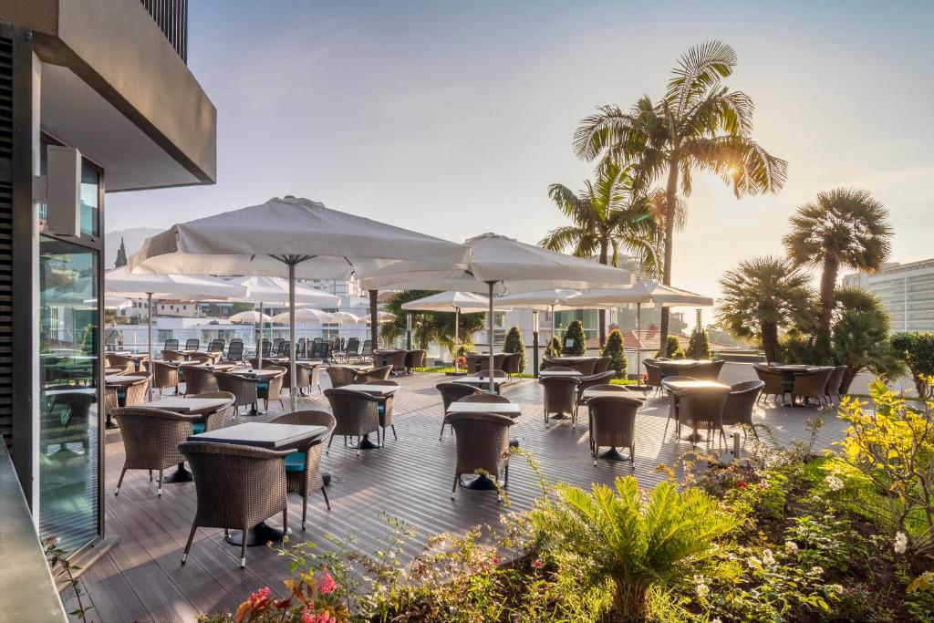 Āra terase ar ērtām mēbelēm un lietussargiem, ko ieskauj zaļumi un palmas, piedāvā relaksējošu atmosfēru saulainā dienā. Ideāla vieta atpūtai un baudīšanai.