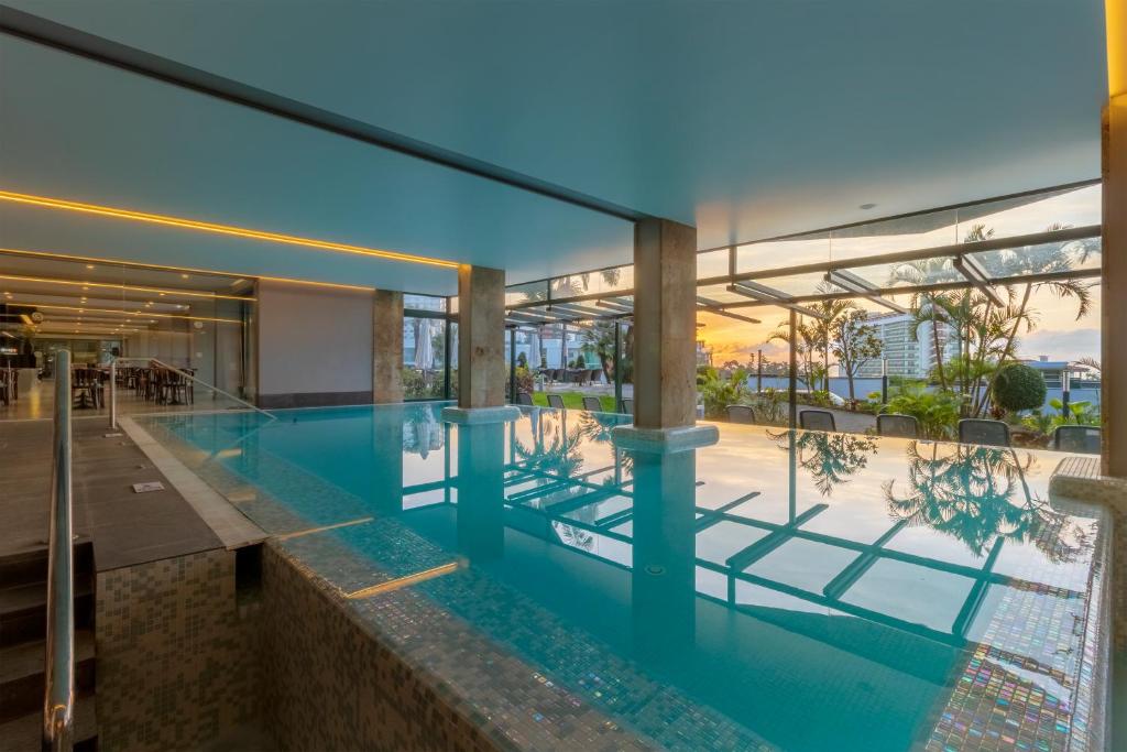 Mūsdienīgs iekštelpu baseins ar lieliskiem skatiem uz dārzu un saulrietu. Interjers ir elegants un apgaismots ar siltu gaismu.