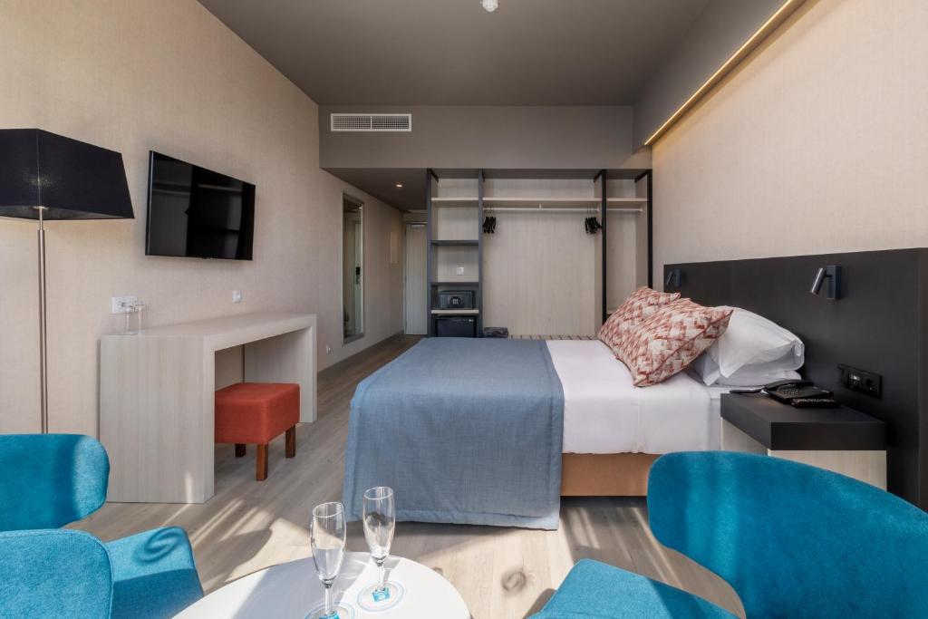 Mūsdienīgs viesnīcas numurs ar ērtu gultu, televizoru un atpūtas zonu. Interjerā ir gaiši toņi un moderna mēbeļu dizaina elementi.