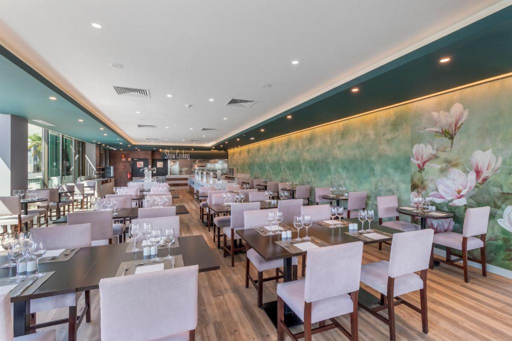 Mūsdienīgs restorāns ar elegantām koka mēbelēm un izsmalcinātu dekoru, kas ietver ziedu motīvus uz sienas. Gaisīga un plaša vide ar daudzām galdiem un krēsliem.