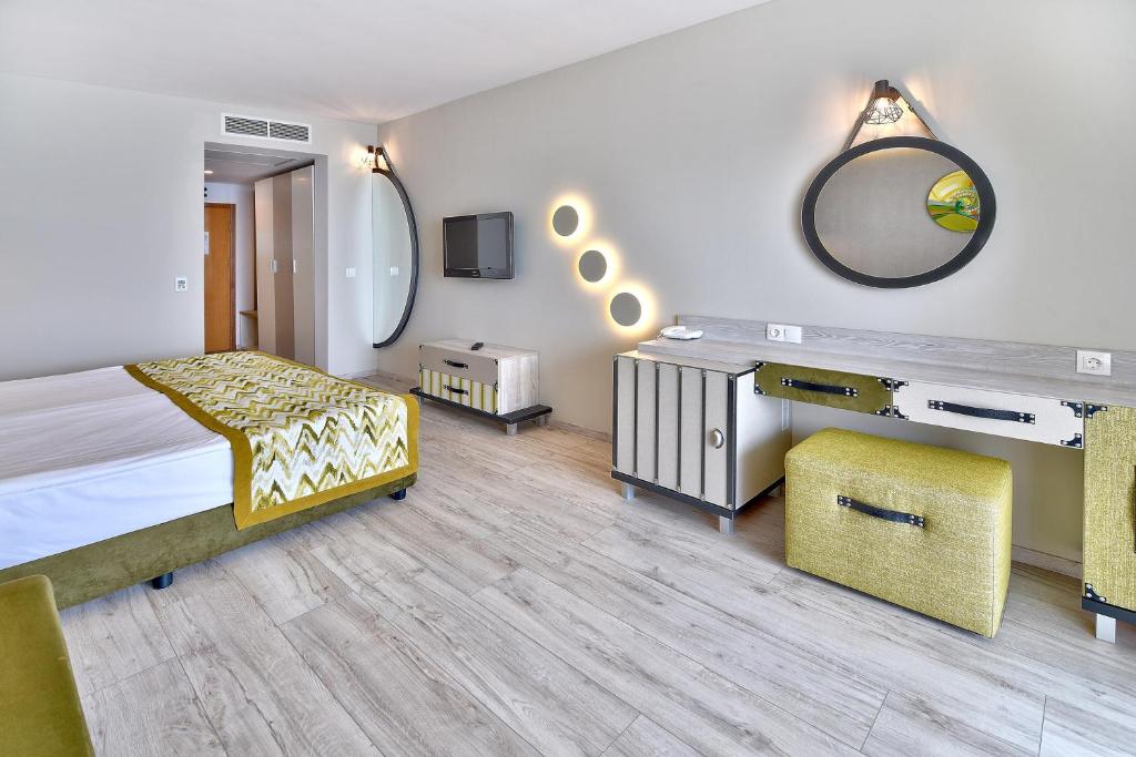 Mūsdienīga viesnīcas numura iekšskats ar divguļamo gultu, stilīgu rakstāmgaldu un lielu spoguli. Interjers ir gaišs un elegants, ar modernas mēbeles un dekoratīviem elementiem.